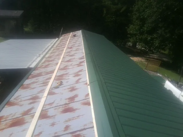 Old rusted panels beside newly installed green metal roofing — Wind Damage Roof Repair by Roofing Brothers in Oakton