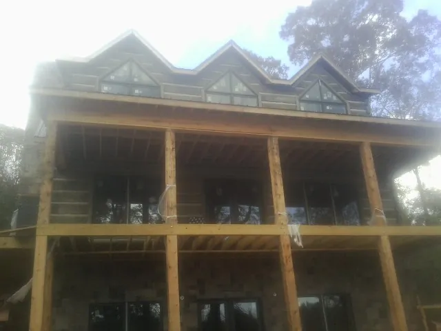 Dormers and porch framing on a large log home under construction — Roof Coating work by our crew in Oakton