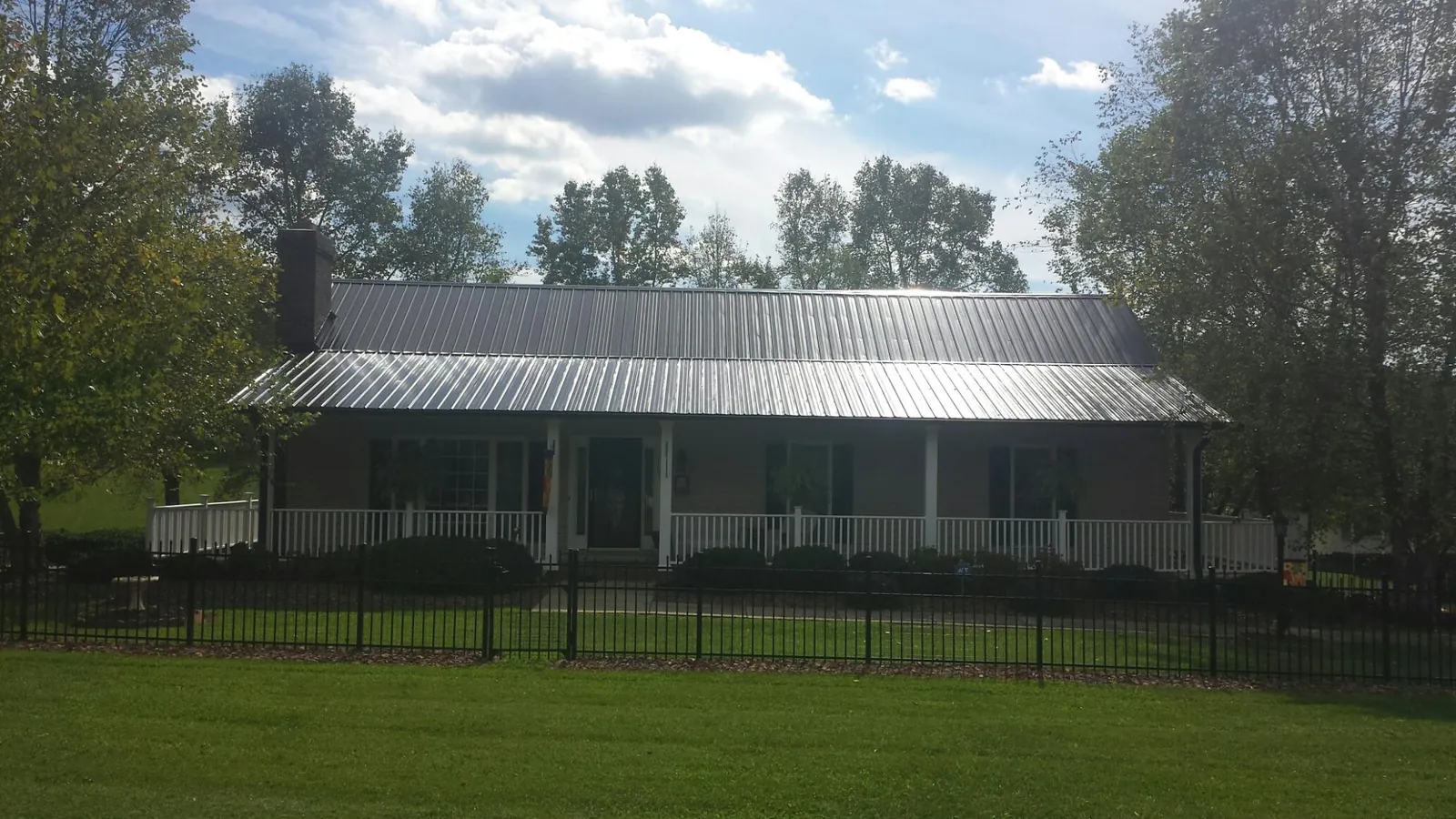 Gray metal roof on a brick ranch with a full width front porch — Gutter Guard Installation work by our crew in Oakton