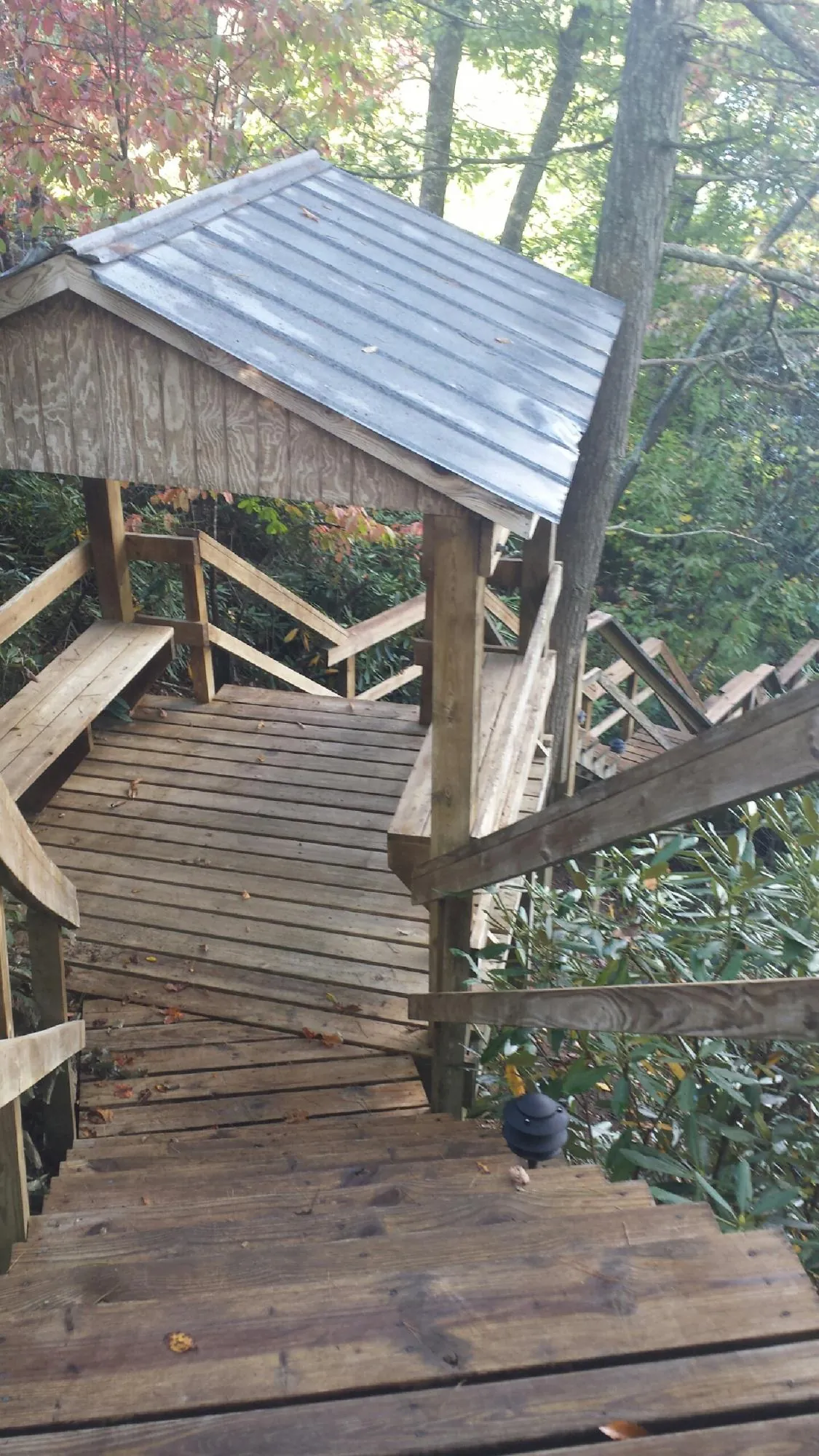 Metal roofed shelter over wooden steps on a wooded walkway — Skylight Repair & Installation work by our crew in Oakton