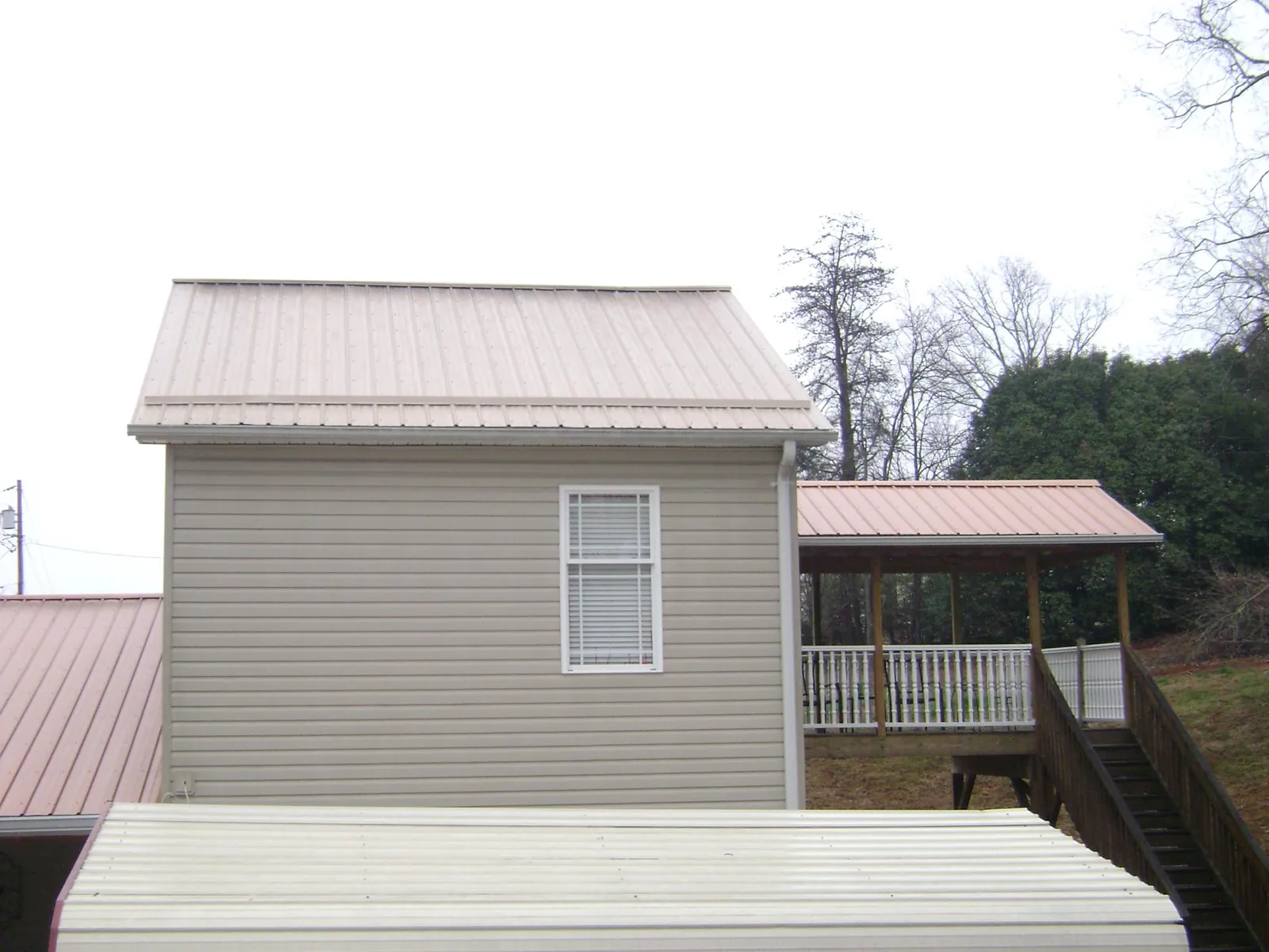Tan metal roofs on a two story addition and attached porch, from a Roof Replacement job in Oakton