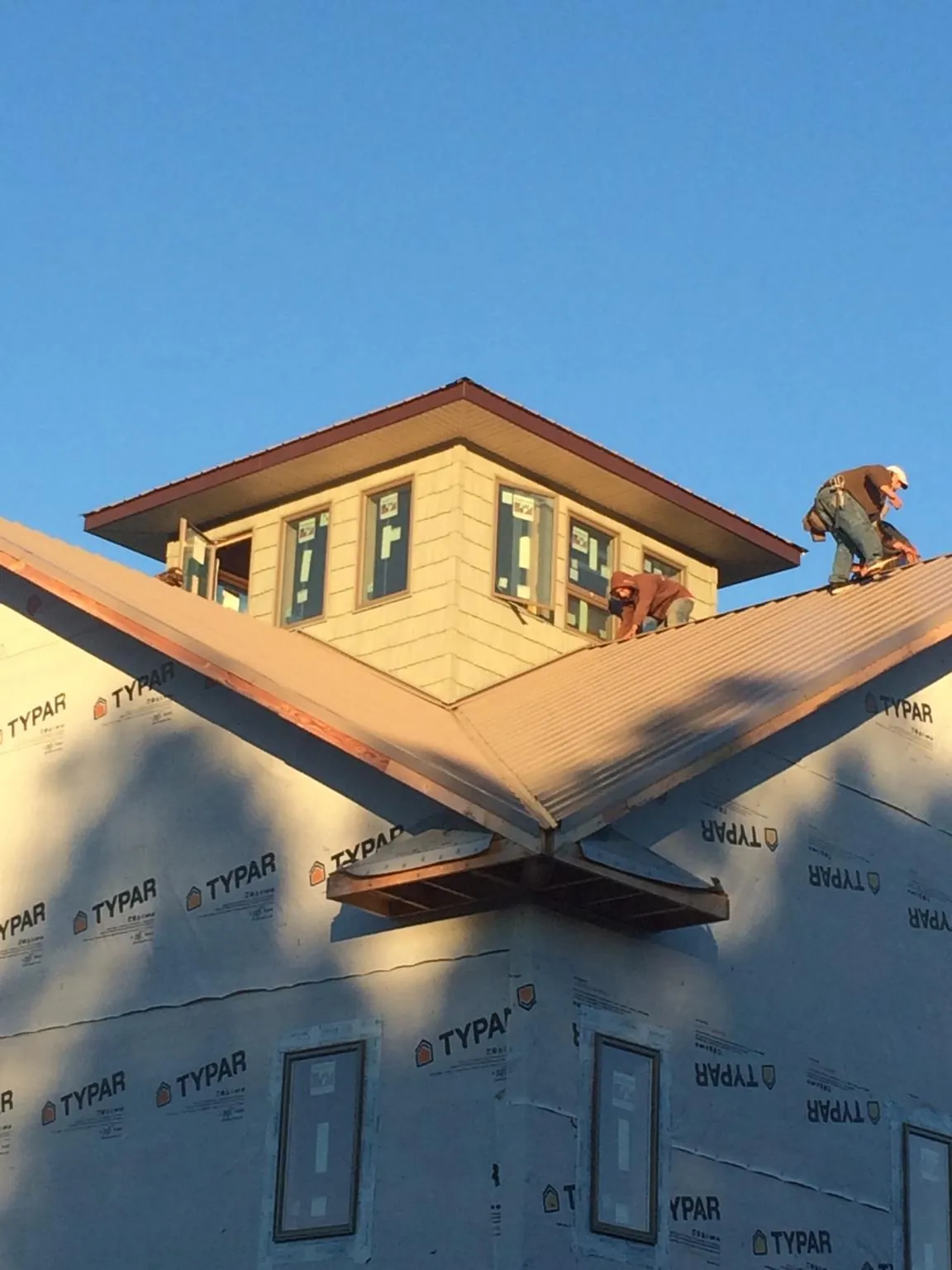 Roofers working around a rooftop cupola on a new metal roof at sunset — Roof Waterproofing in Oakton by Roofing Brothers